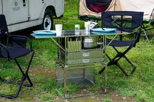 Dare to be Different chuckbox M fully opened and in use at a campsite, surrounded by camping chairs and grass